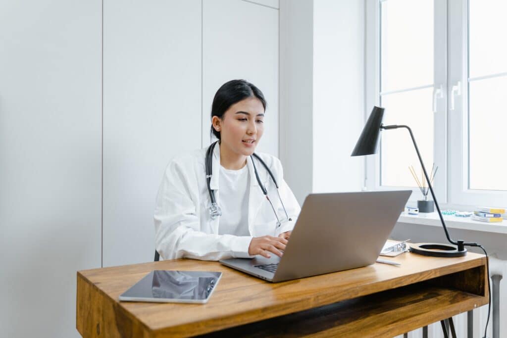 Nurse practitioner working on laptop discussing medical director requirements for aesthetics practices.
